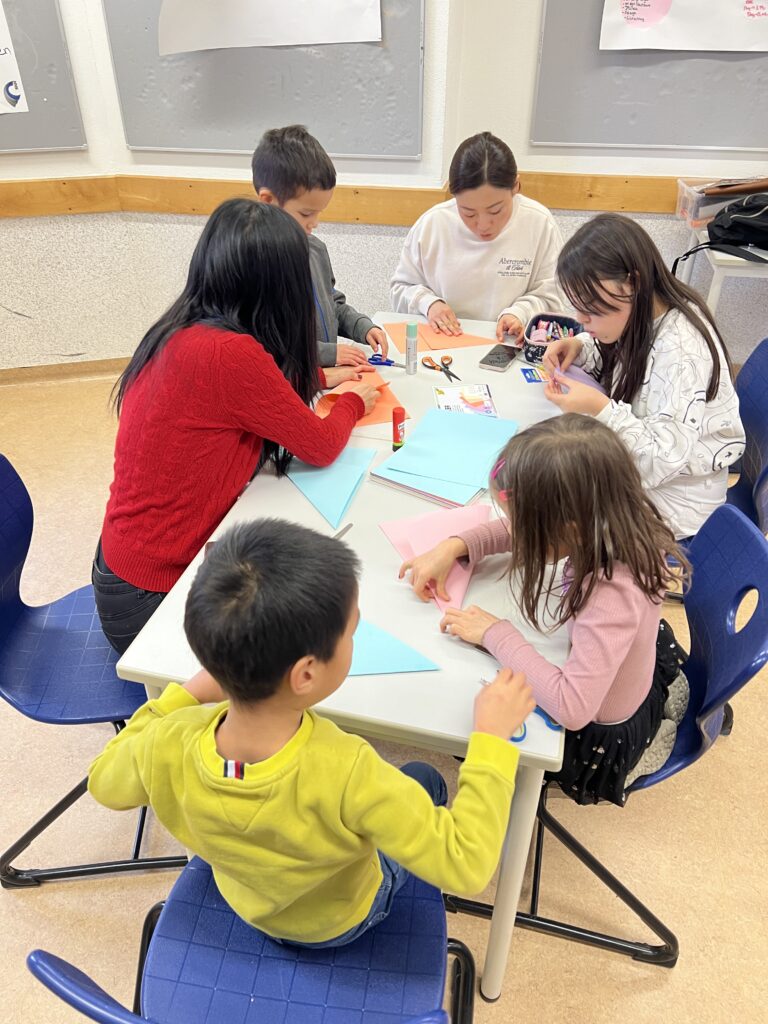 Kinder basteln gemeinsam am Tisch